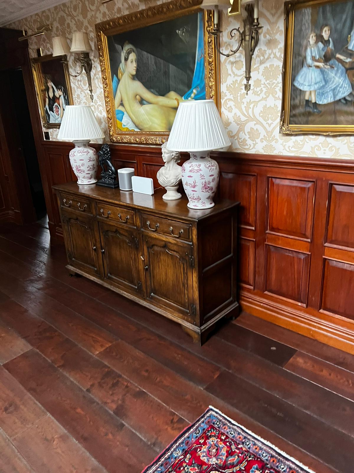 Period hallway with framed paintings and oak sideboard prior to a high-value move