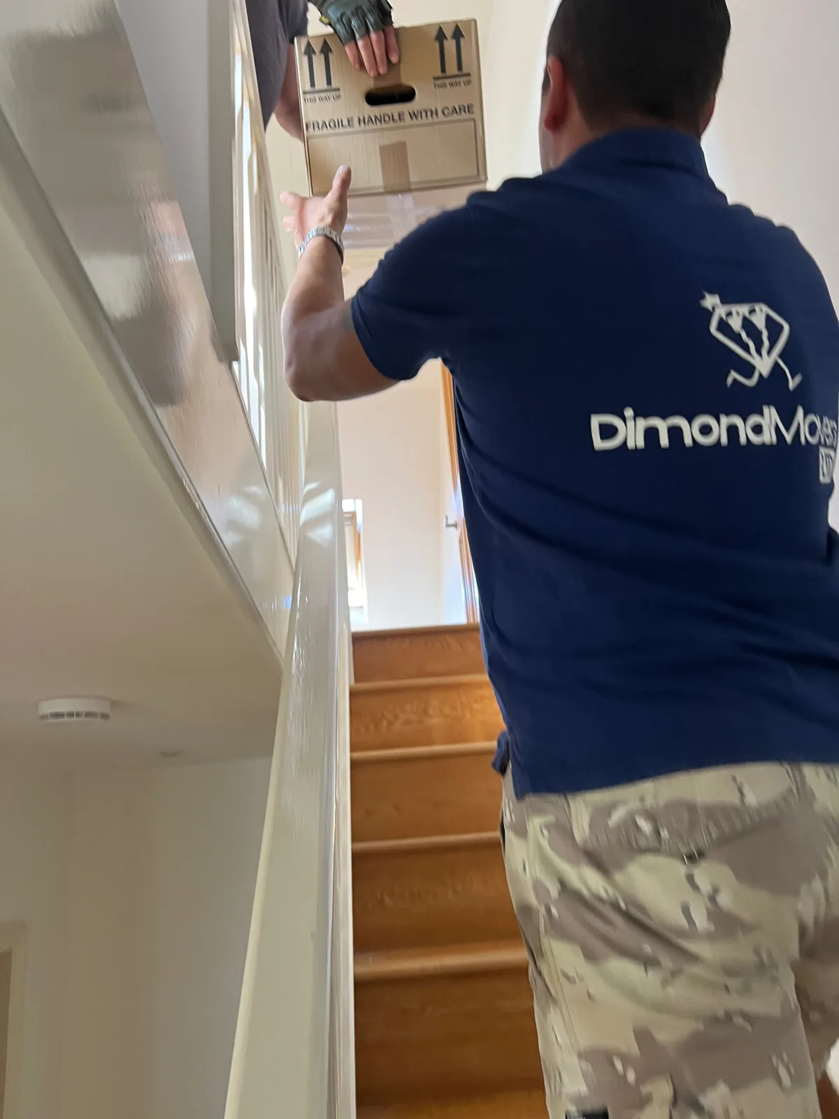 Removals team carrying furniture down a UK staircase